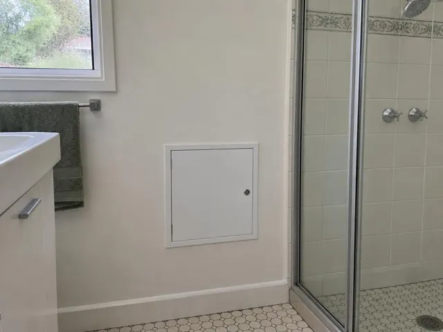 Neat access panel in a bathroom wall beside a tiled shower and vanity in New Lambton